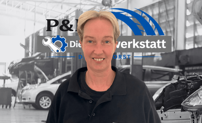 Autowerkstatt Delmenhorst Teammitglied vor Firmenlogo in moderner KFZ-Werkstatt