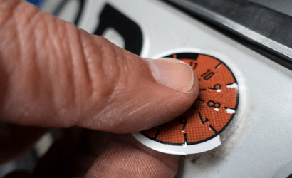 Hand bringt HU-Plakette auf Nummernschild an Kfz-Werkstatt Delmenhorst